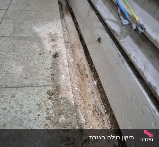 חול ואבנים ליד צינור חשוף ברצפה